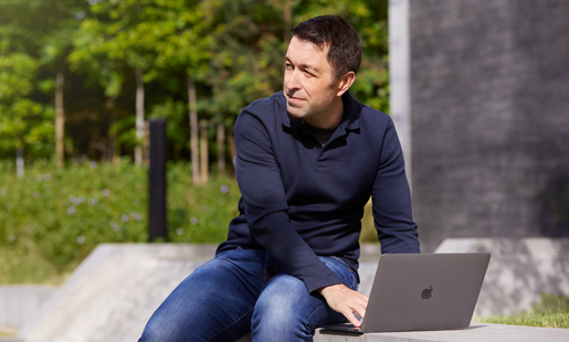 Rob sentado en el campus, trabajando en su laptop.