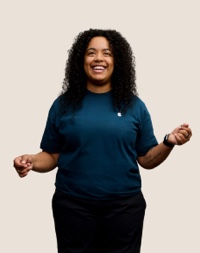 Retrato de una persona del equipo de Apple Retail sonriendo con cabello largo, rizado y oscuro.