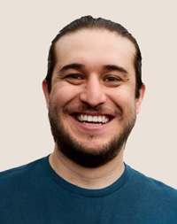Retrato de una persona del equipo de Apple Retail sonriendo con cabello oscuro y barba.