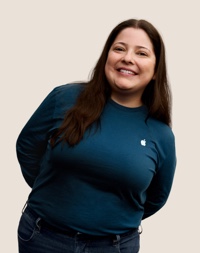Retrato de una persona del equipo de Apple Retail sonriendo con cabello largo oscuro.
