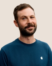 Retrato de una persona del equipo de Apple Retail sonriendo con cabello oscuro y barba.