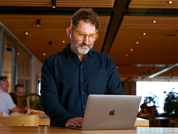 Członek zespołu Apple Corporate Functions korzystający z MacBooka w Caffè Macs.