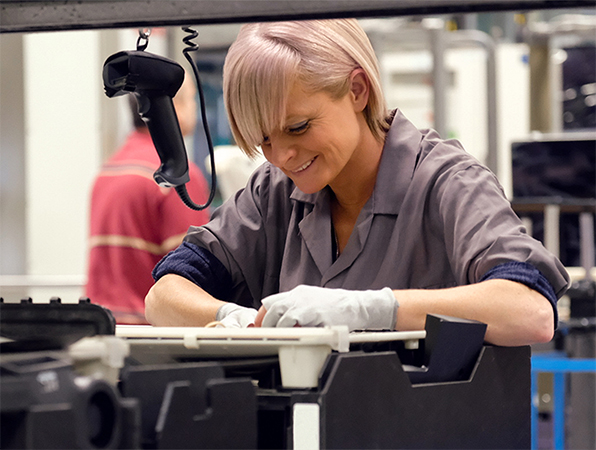 W zakładzie produkcyjnym Apple dwoje pracowników ogląda aluminiowe obudowy MacBooków na tytanowych stelażach do anodyzacji.