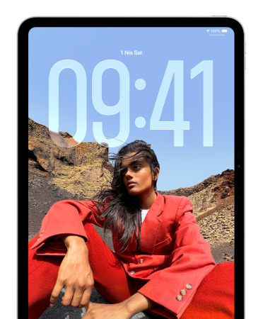iPad Kilit Ekranı’nda, oturan bir kişi fotoğrafının arka planında büyük rakamlarla saat görünüyor