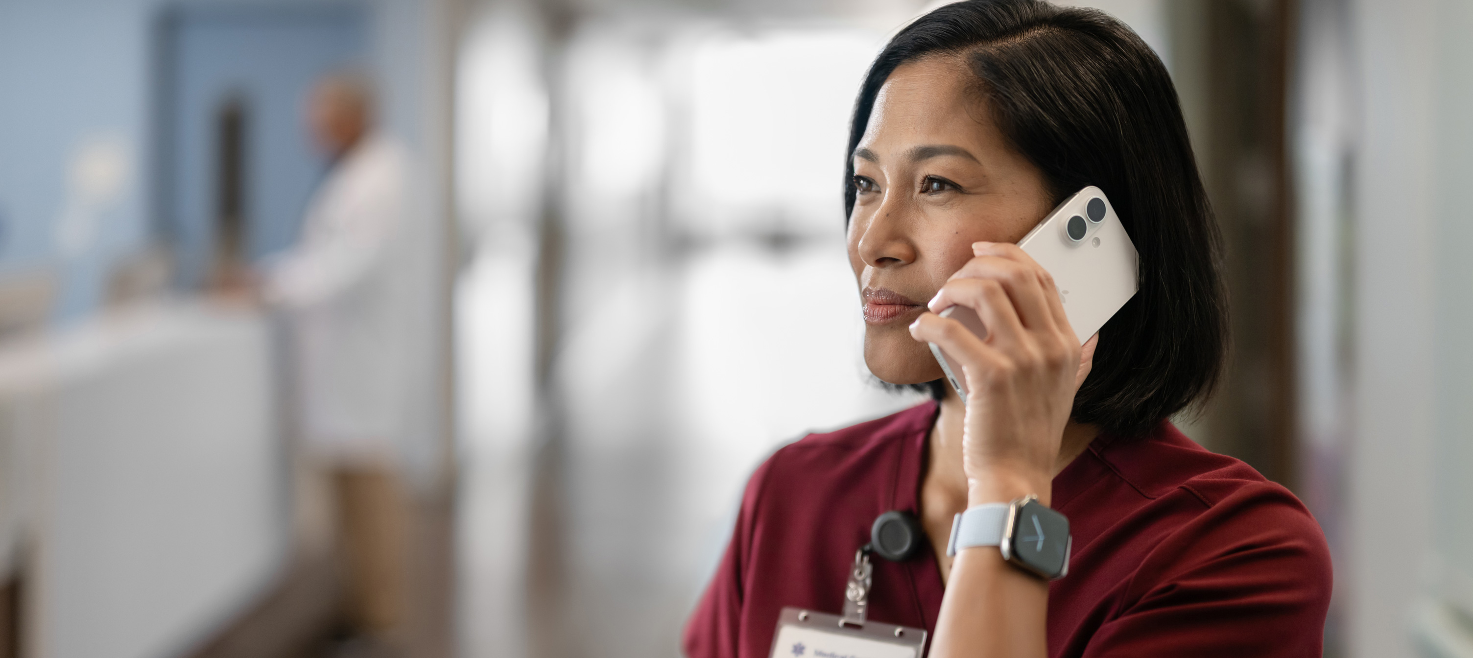 赤色のスクラブを着用し、iPhoneで話している女性看護師