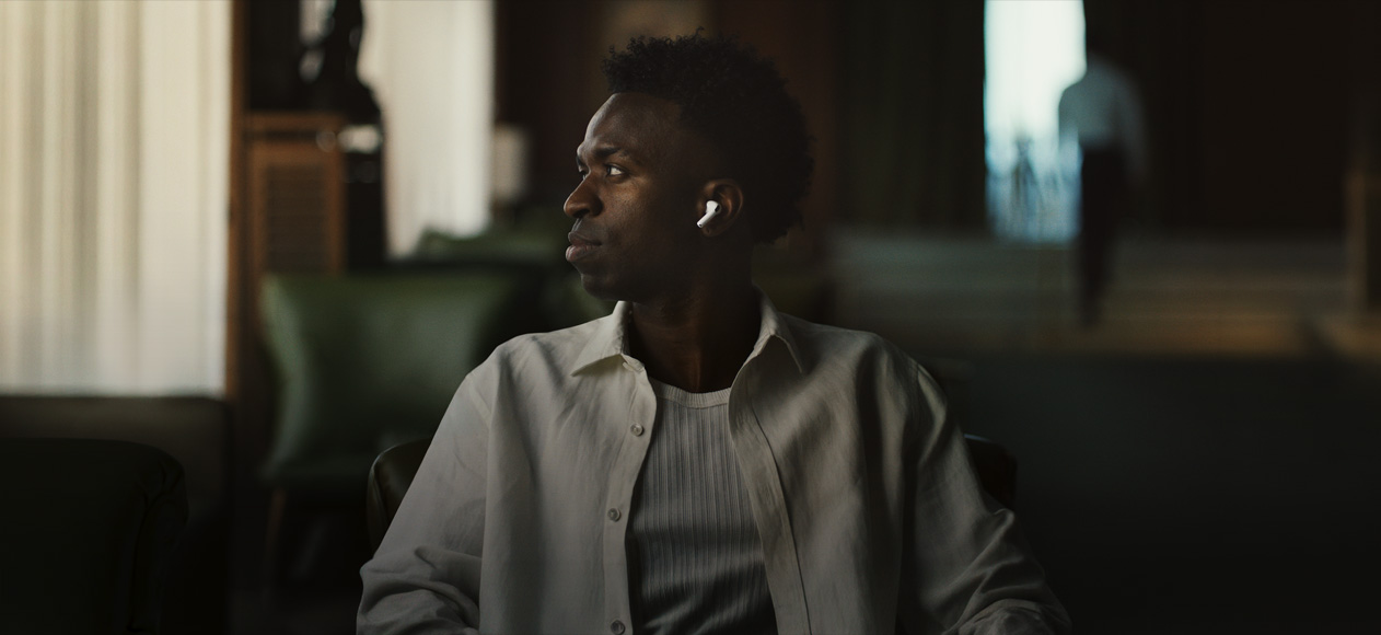 Person wearing white shirt, head turned to the side, left AirPods Pro 3 earbud visible