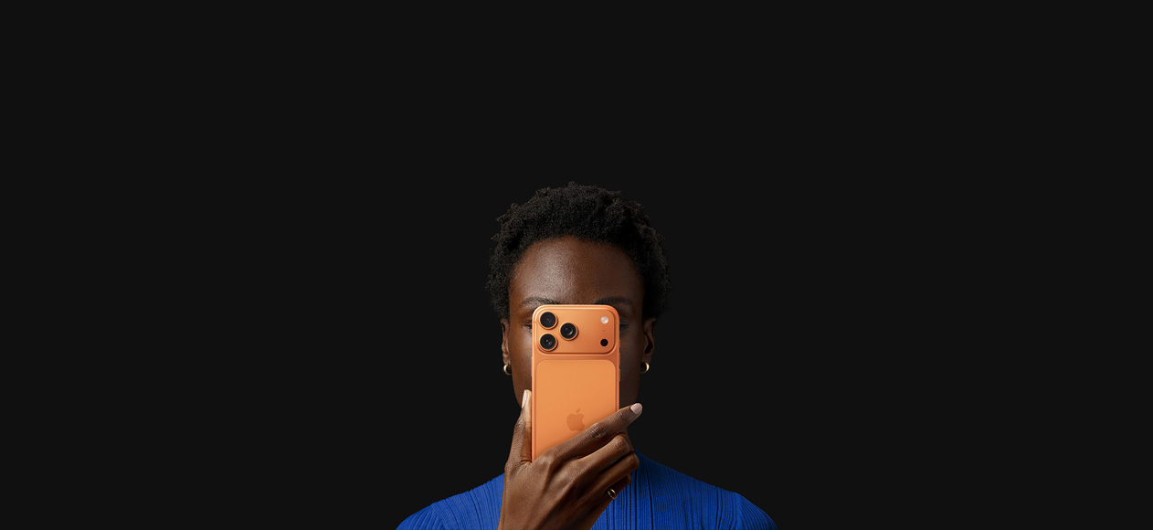 En person holder iPhone 17 Pro foran ansiktet, med baksiden vendt utover, i fargen kosmisk oransje.